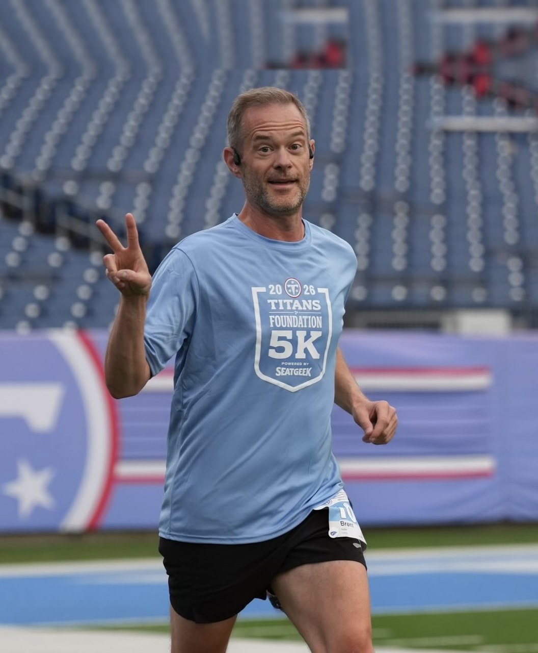Brent Adair flashing a peace sign while running the Titans Foundation 5K